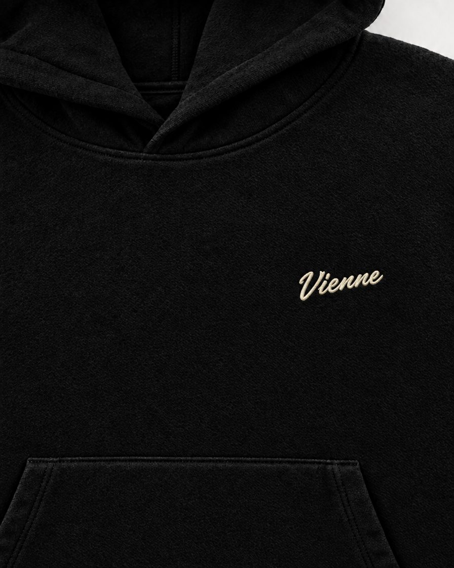 Concept image: close up of the cream Vienne script embroidered on the black Signé Hoodie